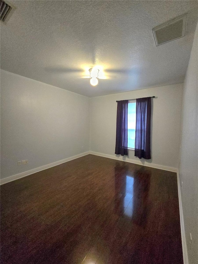 empty room with a textured ceiling and hardwood / wood-style floors