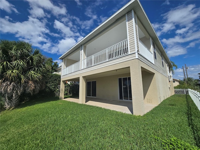 rear view of property with a yard, a patio, and a balcony