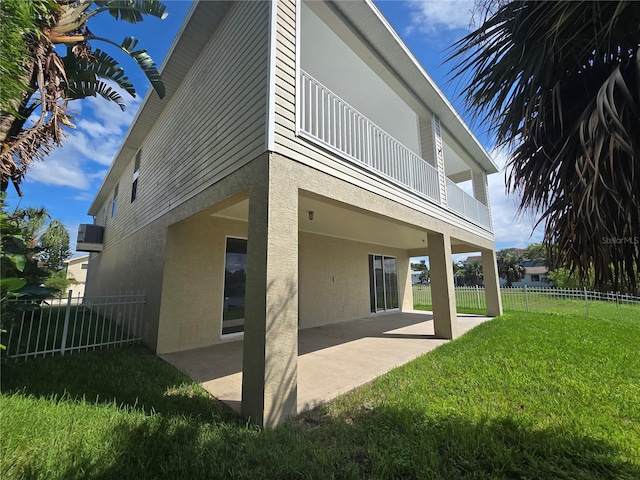 rear view of house with a balcony, a patio area, and a yard