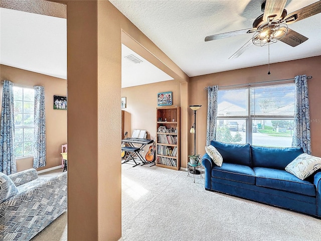 living room featuring ceiling fan, a textured ceiling, light carpet, and a healthy amount of sunlight