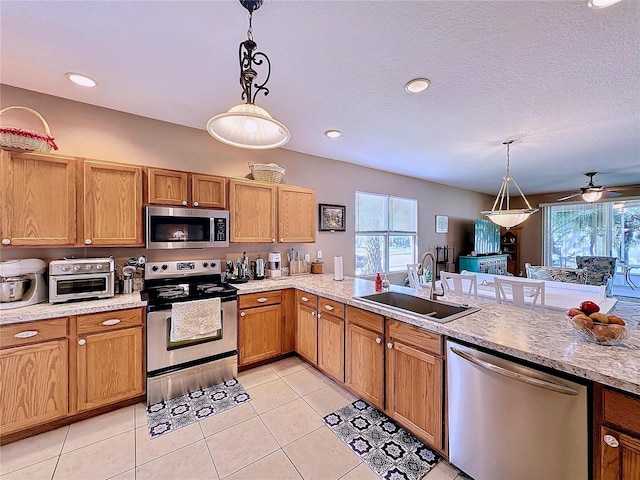 kitchen featuring appliances with stainless steel finishes, hanging light fixtures, sink, and ceiling fan