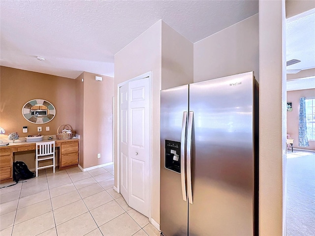 kitchen with a textured ceiling, light tile patterned flooring, and stainless steel fridge with ice dispenser