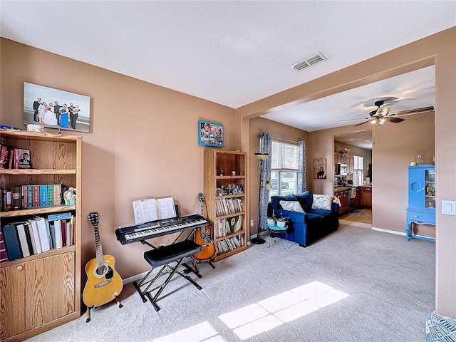 miscellaneous room with light carpet, ceiling fan, and a textured ceiling