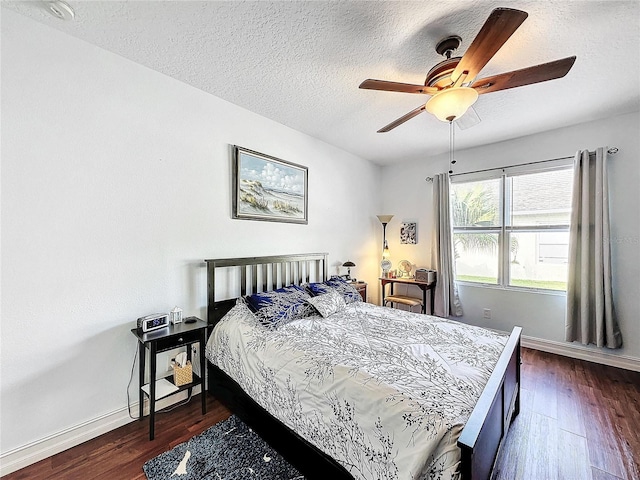 bedroom with ceiling fan, a textured ceiling, and dark wood-type flooring