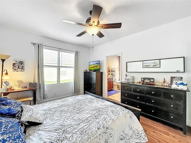 bedroom featuring ceiling fan, a textured ceiling, light hardwood / wood-style flooring, and connected bathroom