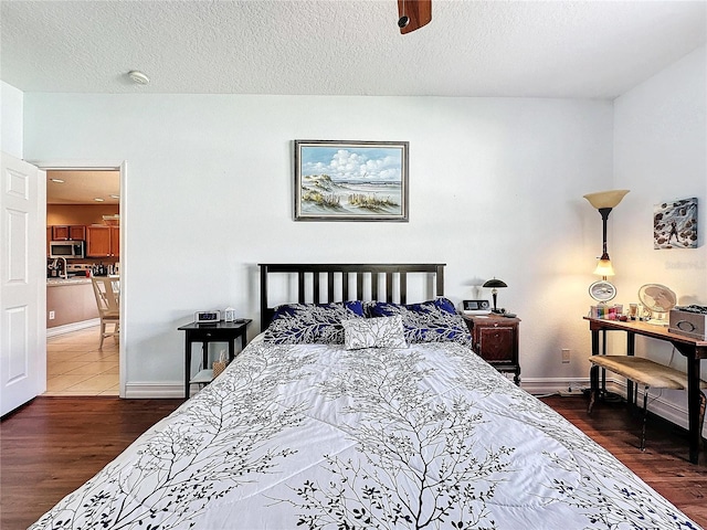 bedroom with a textured ceiling, dark hardwood / wood-style floors, and ceiling fan