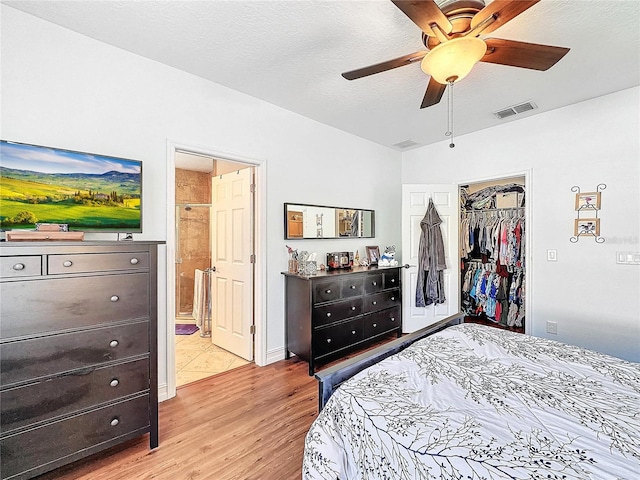 bedroom with a closet, light wood-type flooring, a textured ceiling, ceiling fan, and ensuite bathroom