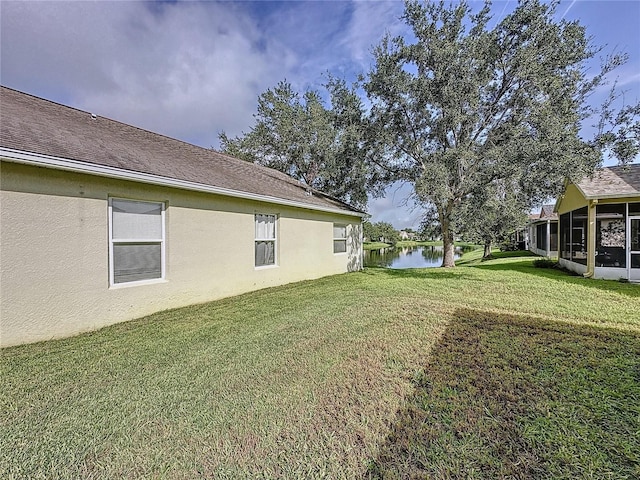 view of yard featuring a sunroom and a water view