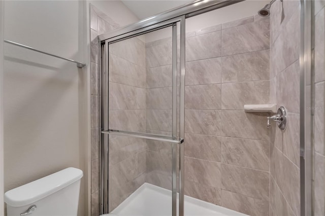 bathroom with a shower with shower door and toilet