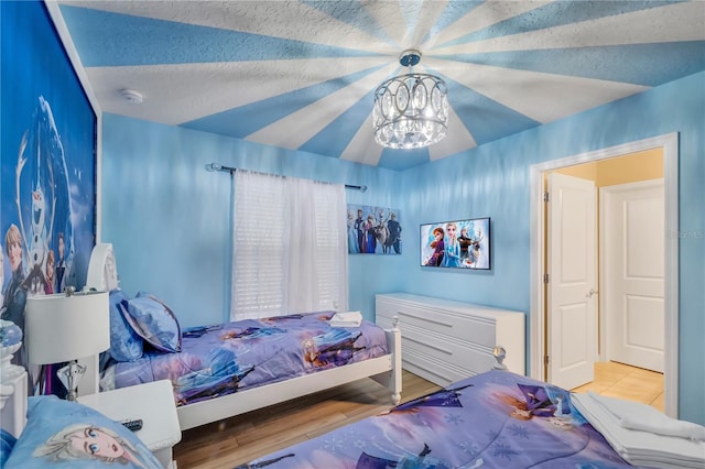 bedroom featuring a textured ceiling, light hardwood / wood-style floors, vaulted ceiling, and a notable chandelier