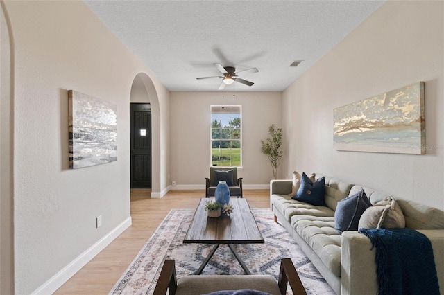 living room featuring ceiling fan, a textured ceiling, and light hardwood / wood-style floors