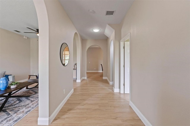 hall with a textured ceiling and light hardwood / wood-style floors