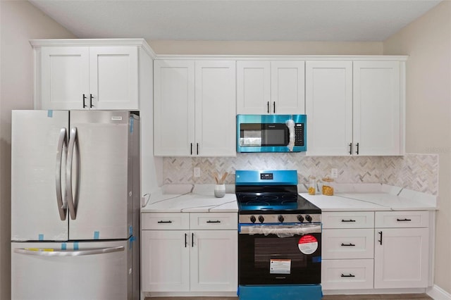 kitchen with light stone countertops, stainless steel appliances, white cabinetry, and decorative backsplash