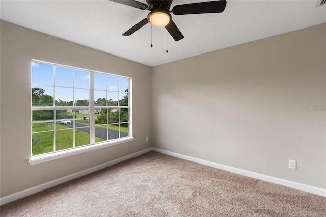 carpeted spare room featuring a healthy amount of sunlight and ceiling fan