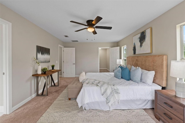 bedroom featuring multiple windows, light colored carpet, and ceiling fan