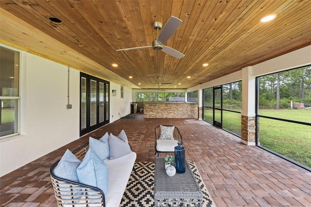 sunroom with ceiling fan and wooden ceiling