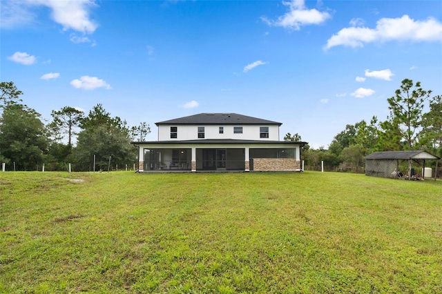 rear view of house featuring a lawn, an outdoor structure, and a sunroom