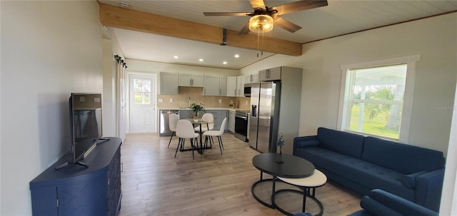 living room featuring beamed ceiling, ceiling fan, a healthy amount of sunlight, and light wood-type flooring