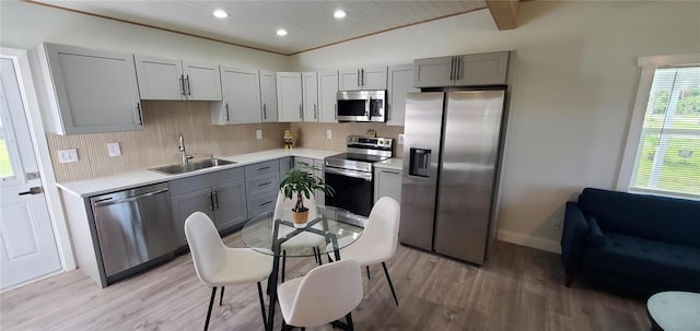 kitchen featuring appliances with stainless steel finishes, light hardwood / wood-style floors, gray cabinetry, and sink