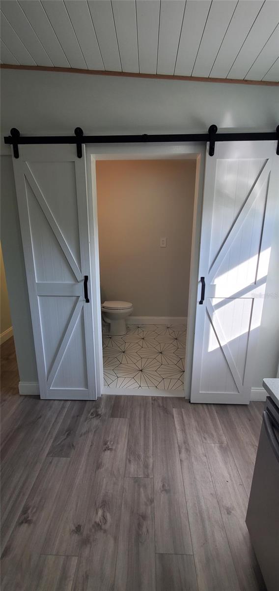 bathroom with wood-type flooring, toilet, ornamental molding, and wood ceiling