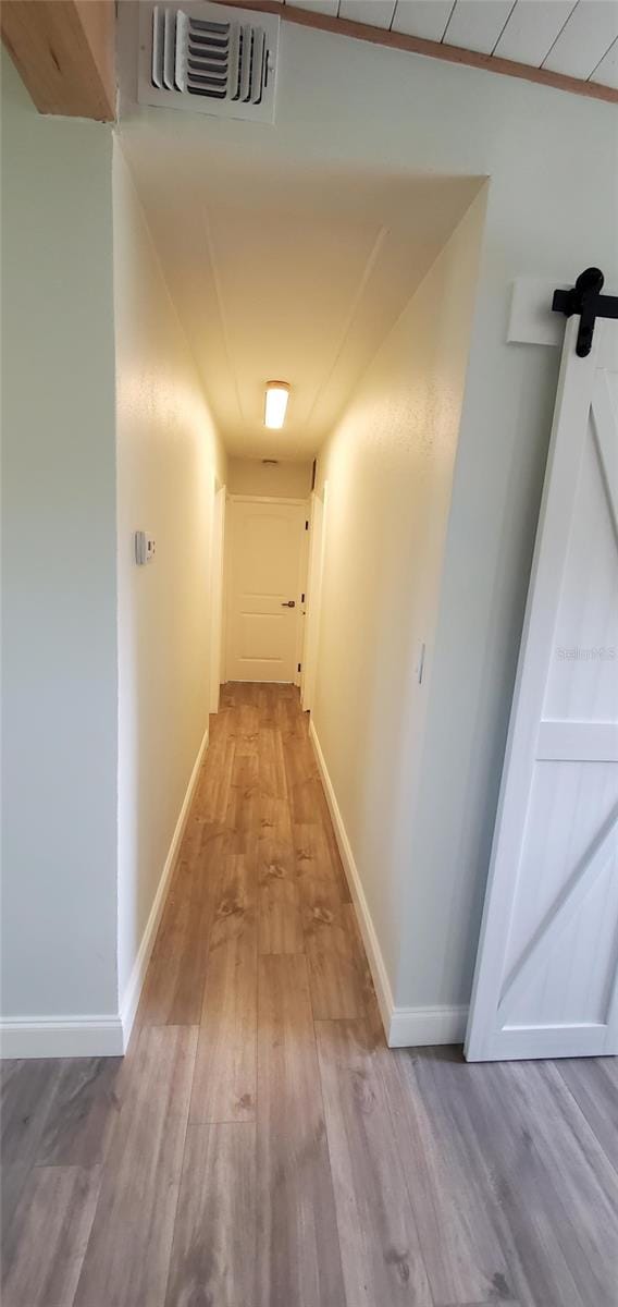 corridor featuring light wood-type flooring and a barn door