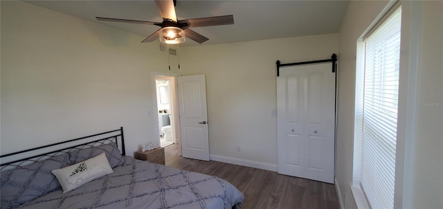 bedroom featuring hardwood / wood-style floors, a barn door, and ceiling fan