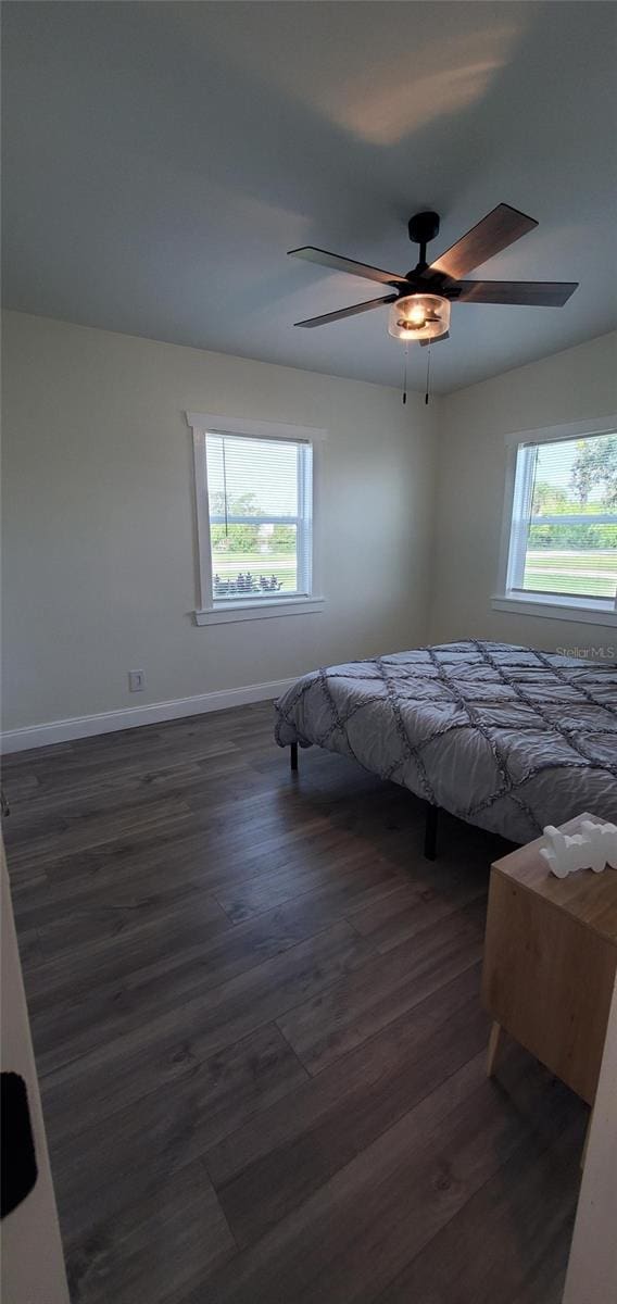 unfurnished bedroom featuring dark hardwood / wood-style flooring, multiple windows, and ceiling fan