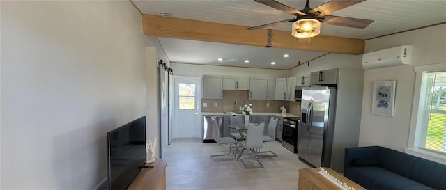 kitchen with a barn door, appliances with stainless steel finishes, a wealth of natural light, and a wall mounted AC