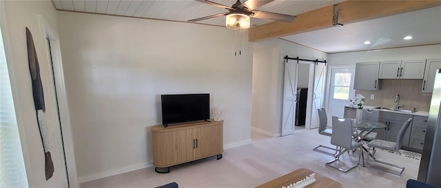 interior space with a barn door, baseboards, ceiling fan, gray cabinets, and a sink