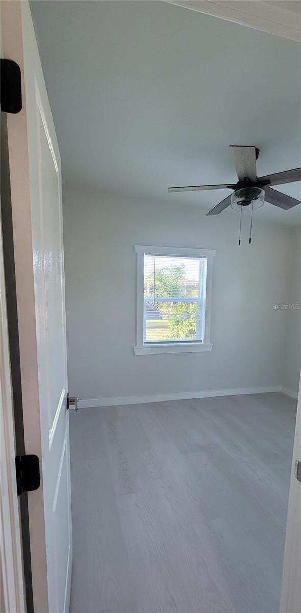 spare room featuring a ceiling fan, baseboards, and wood finished floors