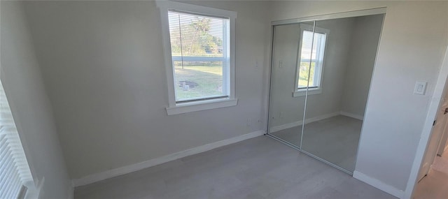 unfurnished bedroom featuring multiple windows, a closet, and baseboards