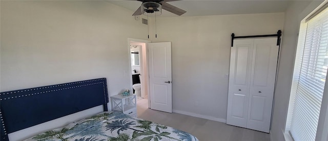 bedroom with wood finished floors, visible vents, baseboards, and a barn door