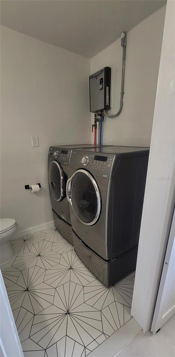 clothes washing area featuring laundry area, independent washer and dryer, tile patterned flooring, and baseboards