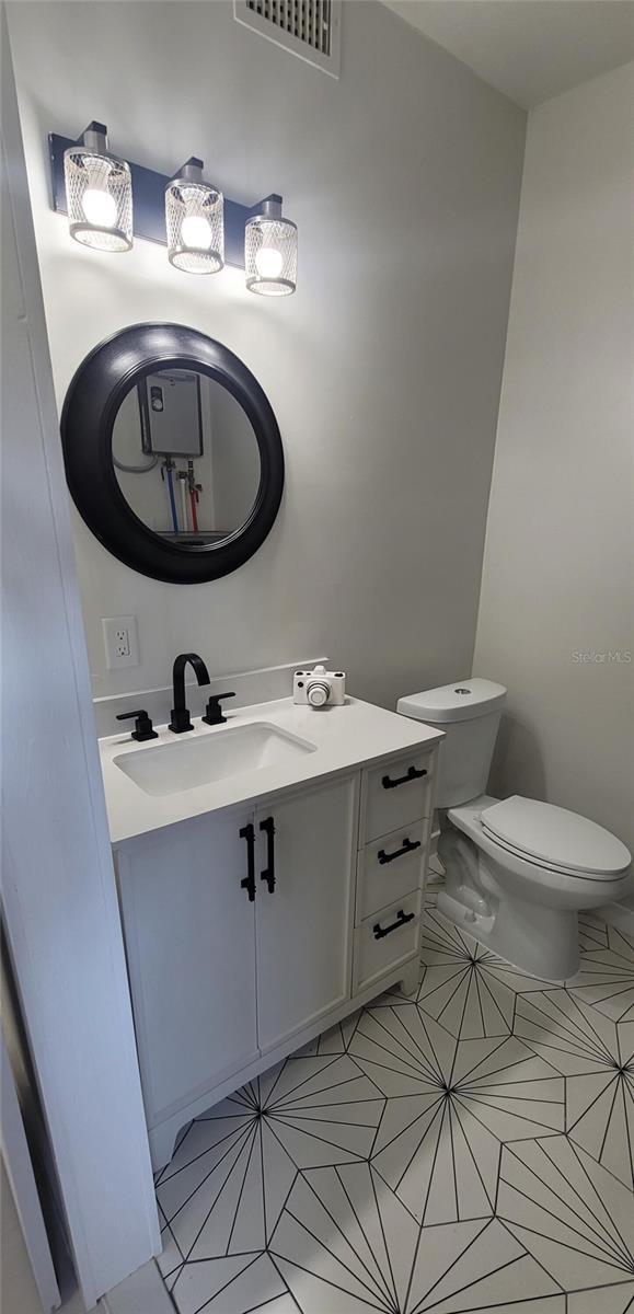 bathroom with toilet, tile patterned flooring, visible vents, and vanity