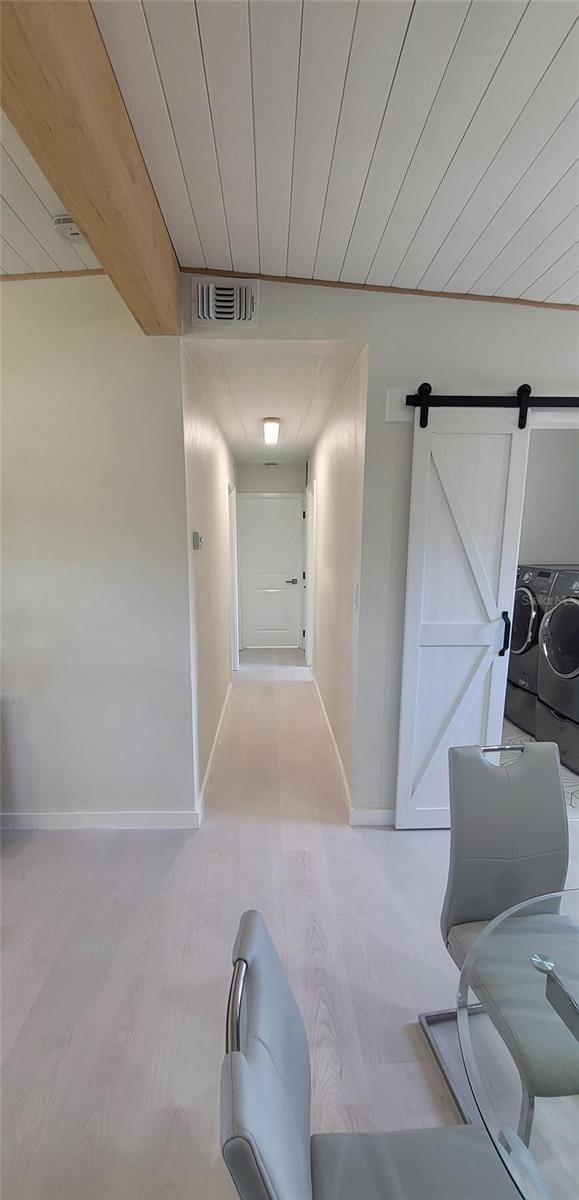 hall featuring washer and clothes dryer, wooden ceiling, visible vents, and baseboards