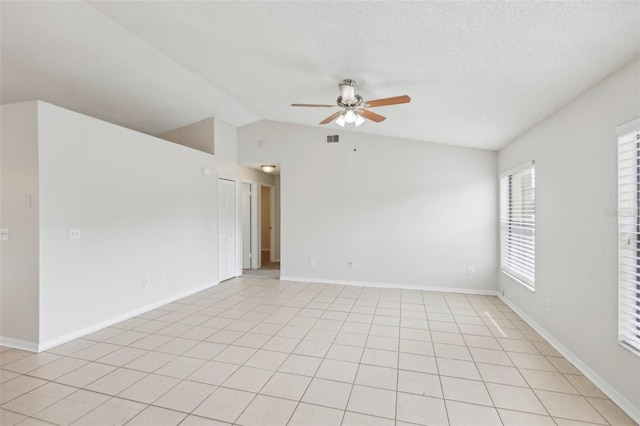 empty room with lofted ceiling, ceiling fan, and light tile patterned flooring