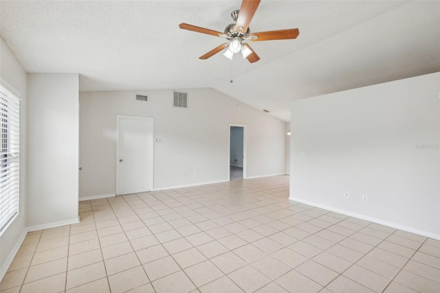 spare room with ceiling fan, light tile patterned floors, and vaulted ceiling