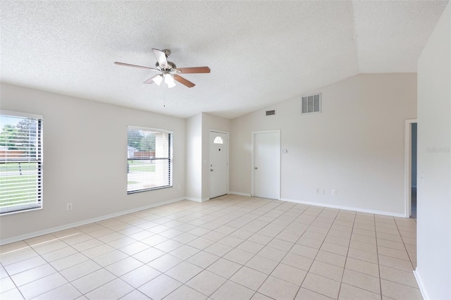 spare room with ceiling fan, light tile patterned flooring, vaulted ceiling, and a wealth of natural light