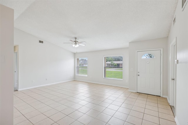 tiled foyer entrance featuring ceiling fan, a textured ceiling, and vaulted ceiling