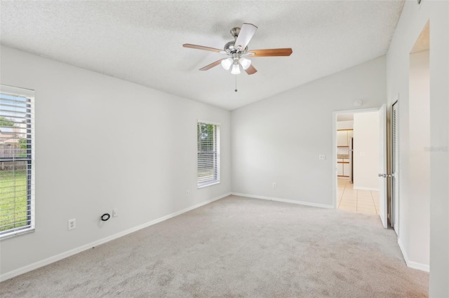 unfurnished room with a textured ceiling, vaulted ceiling, ceiling fan, and light colored carpet