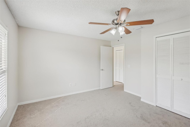 unfurnished bedroom featuring a textured ceiling, ceiling fan, light colored carpet, and a closet