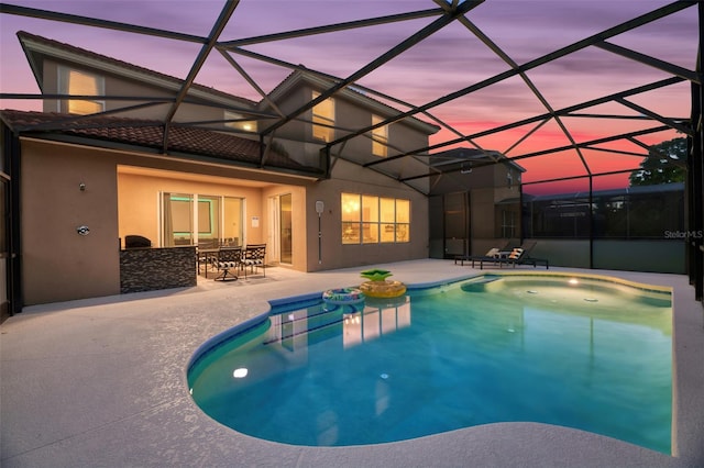 pool at dusk featuring a lanai and a patio