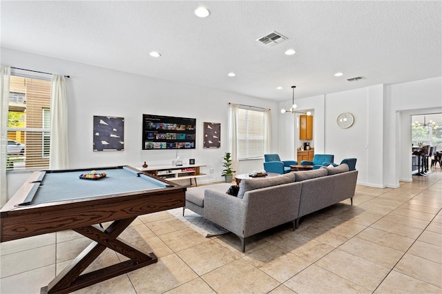 tiled living room with a textured ceiling, billiards, and an inviting chandelier