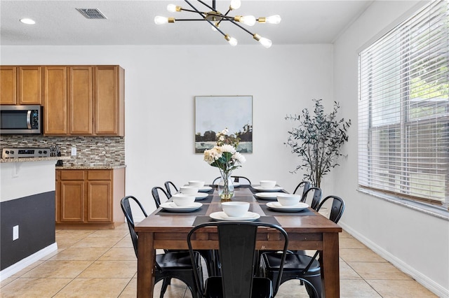 tiled dining room featuring a notable chandelier and a textured ceiling