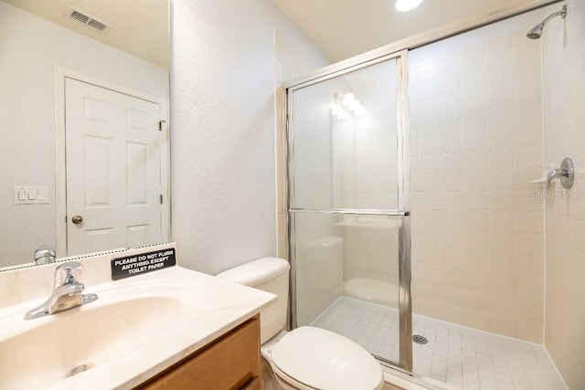 bathroom featuring vanity, toilet, and a shower with shower door