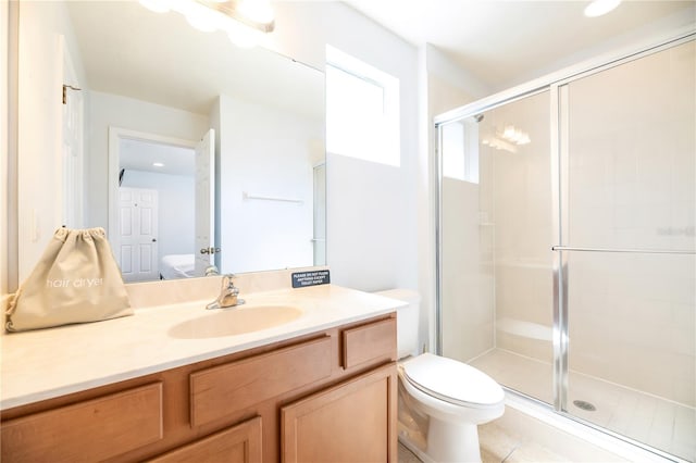 bathroom featuring a shower with door, vanity, toilet, and tile patterned floors