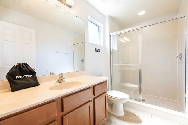 bathroom with a shower with door, vanity, toilet, and tile patterned floors