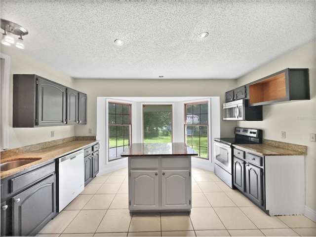 kitchen with light tile patterned floors, a kitchen island, stainless steel appliances, and a textured ceiling