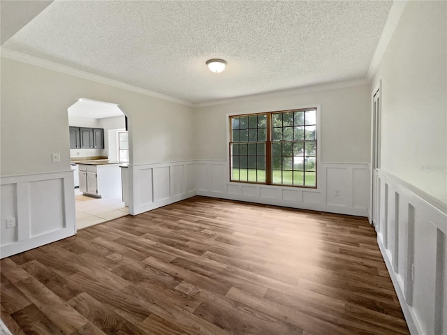 unfurnished room with a textured ceiling, crown molding, and wood-type flooring