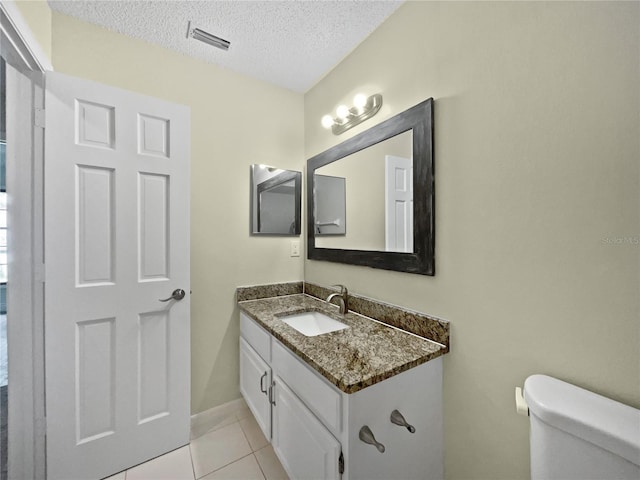 bathroom featuring a textured ceiling, vanity, toilet, and tile patterned flooring